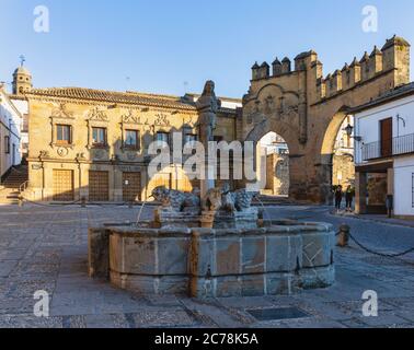 Fuente de los Leones, oder Brunnen des Löwen, in der Plaza del Populo, Baeza, Provinz Jaen, Andalusien, Spanien. Die ornamentale City Gate in der Rückseite Stockfoto