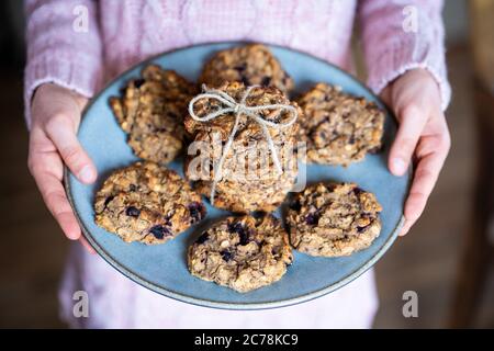 Kind serviert einfach zuzubereiten und gesund, hausgemachte Haferflocken und Blaubeer-Kekse auf einem blauen Teller. Stockfoto