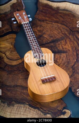 Kleines Instrument - hellbraune Ukulele auf schönem Holztisch. Stockfoto