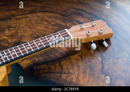 Nahaufnahme eines Ukulele Griffbretts - kleines hellbraunes Instrument auf einem schönen Holztisch. Stockfoto