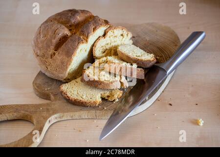 Frisch gebackenes irisches Sodabrot, das in Scheiben geschnitten wurde, mit einem großen Messer, das auf der Seite liegt. Gesundes, hausgemachtes, leckeres Gebäck. Stockfoto