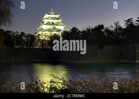 Nachtaufnahme des Hauptmogs der Burg von Nagoya mit Blick auf den weitläufigen Graben um sie während einer Winternacht. Stockfoto