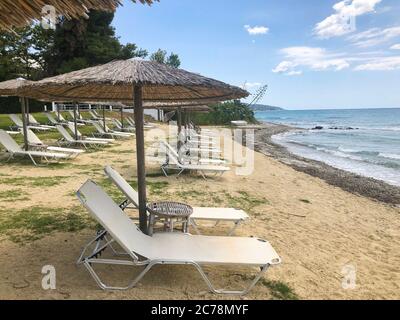 Liegestühle und Sonnenschirme an einem verlassenen Strand. Corona Virus Quarantäne in einer Sommerzeit Stockfoto