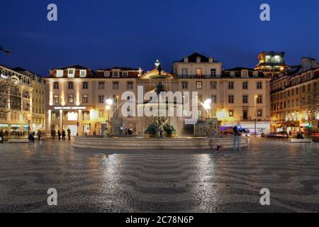 Südseite des zentralen Rossio Platzes in Lissabon, Portugal. In der Mitte befindet sich einer der beiden barocken Brunnen, die den großen Platz mit Welle-l schmücken Stockfoto