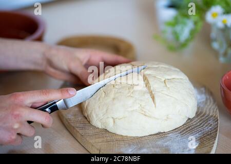 Hände eines Mädchens, das Messer hält und Kreuz auf leicht zuzubereiten und gesund, hausgemachtes irisches Sodabrot. Hausbäckerei. Stockfoto