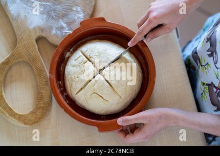 Hände eines jungen Mädchens, das Messer hält und Kreuz auf leicht zuzubereiten und gesund, hausgemachtes irisches Sodabrot macht. Hausbäckerei. Stockfoto