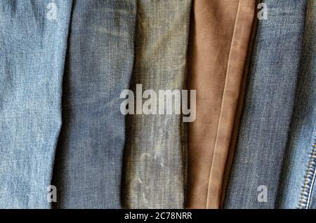 Mehrfarbige Jeans auf der Ladentheke. Demonstration verschiedener Farbtöne von Denim-Hosen. Moderne Freizeitkleidung. Draufsicht in einem Winkel. Selektive FOC Stockfoto