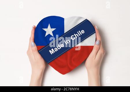 Inschrift in Chile die Flagge von Chile. Weibliche Hände halten eine herzförmige Box. Weißer Hintergrund. Stockfoto