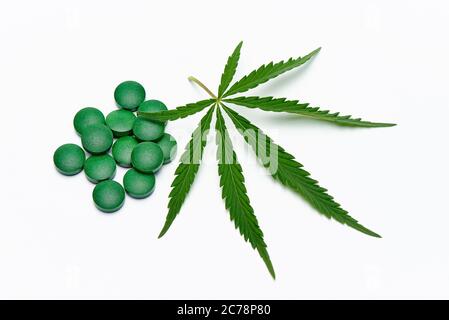 Cannabisblatt und Tabletten auf weißem Hintergrund. Stockfoto