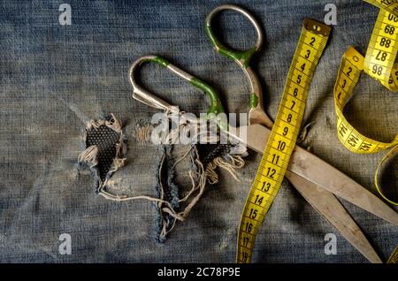 Schneiderschere, Maßband auf zerrissenen Jeans. Reparaturservice für Kleidung. Blick von oben. Selektiver Fokus. Stockfoto