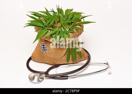 Jute-Beutel mit Cannabis und einem Stethoskop auf weißem Hintergrund. Stockfoto