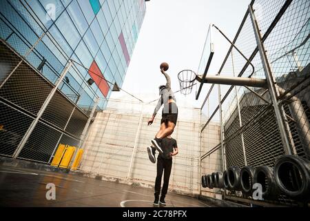 Junge asiatische Basketballspieler Dunking den Ball auf dem Freiplatz Stockfoto