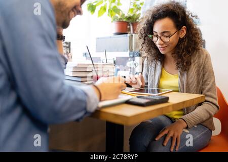 Universitätsstudenten in Zusammenarbeit an der Bibliothek. Gruppe junger Freunde, die Bücher lesen. Stockfoto