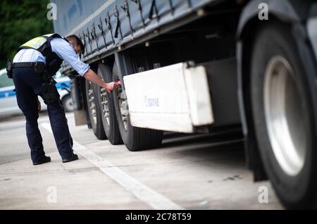 Unna, Deutschland. Juli 2020. Ein Polizist überprüft die Temperatur der Bremsscheiben eines LKW auf dem Parkplatz Kolberg auf der Autobahn 2 in Richtung Hannover. Die Bezirkspolizei Unna führt zusammen mit dem Landesamt für Bildung, Weiterbildung und Personalwesen (LAFP) und Zoll umfangreiche LKW-Inspektionen durch. Der Schwerpunkt der Kontrollen liegt auf der Einhaltung der Sozialvorschriften. Quelle: Jonas Güttler/dpa/Alamy Live News Stockfoto