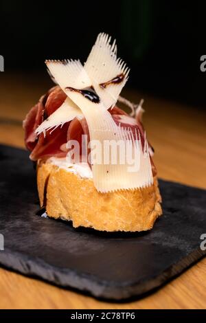 Bruschetta mit Speck und Käse mit weißem Weizenbrot auf einem schwarzen Tablett Schweinefleisch Sandwich. Stockfoto