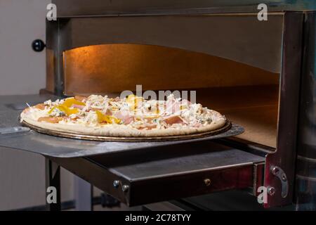 Die Pizza auf der Schaufel wird im Ofen gebraten. Der Prozess der Herstellung von italienischen Pizza in einem Restaurant. Stockfoto
