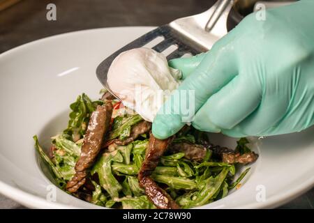 Kalbsbartensalat und pochiertes Ei. Warmer Salat mit Fleisch im Restaurant Stockfoto