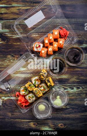 Lebensmittelzustellung nach Hause: Sushi, Brötchen in Einweg-Plastikbehältern. Traditionelle japanische Küche, Meeresfrüchte. Stockfoto