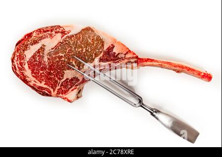 Trocken im Alter von Raw tomahawk Rindersteak auf weißem Hintergrund, Vorderansicht, close-up mit Fleisch Gabel Stockfoto