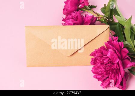 Briefumschlag schöne burgunderrote Pfingstrosen. Flaches Layout mit Blumenhintergrund. Rahmen von frischen Blumen. Urlaubskonzept. Stockfoto