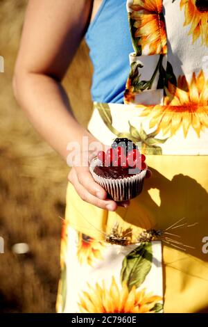 Mädchen hält einen Schokoladenmuffin mit Früchten verziert. Food-Fotografie. Stockfoto