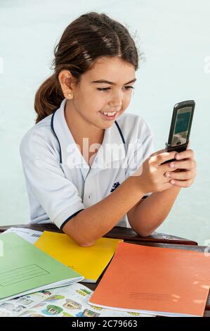 Flip Phone alt Motorola Technologie Junior Schulmädchen 7-9 Jahre im Freien Studie in sonnigen Schulhof mit Handy-Handy, um SMS Stockfoto