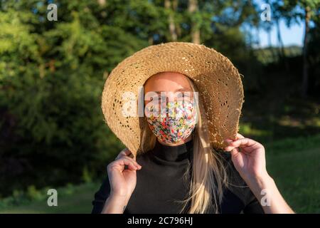 Schöne junge Frau trägt eine stilvolle modische Coronavirus Gesichtsmaske während Covid-19 Pandemie Lockdown Stockfoto