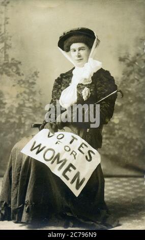 Suffragette sitzend, 1910 Postkarte einer Kämpferin für Frauenstimmen mit dem Plakat über ihrem Schoß Stockfoto
