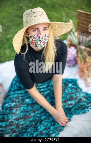 Porträt einer Frau mit blonden Haaren, die eine Gesichtsmaske mit Coronavirus während der Pandemie-Sperre von Covid-19 trägt Stockfoto