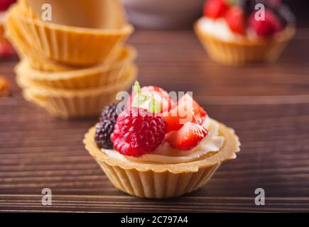 Köstliche Mini-Tartlets mit frischen Beeren auf Holzhintergrund. Stockfoto