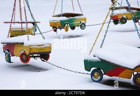 Im Winter verlassene Karussells. Leerer Kinderspielplatz im Wintertag. Kinderwagen hängen Stockfoto