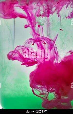 Eine Nahaufnahme von Rosa und Grün Farbe gemischt in Wasser. Stockfoto