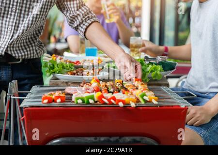 Ein Mann grillen Schweinefleisch und Grill in der Dinner-Party. Essen, Menschen und Familie Zeitkonzept. Stockfoto