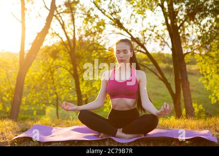 Mädchen sitzt mit geschlossenen Augen auf einem weichen Teppich. Stockfoto