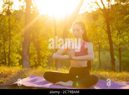 Das Mädchen sitzt auf dem Teppich und die Sonne scheint in die Kamera Stockfoto