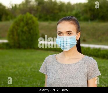 Porträt einer Frau in medizinischer Maske auf ihrem Gesicht im Freien. Stockfoto