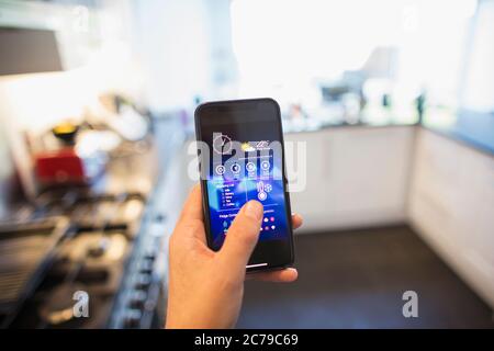 POV man Anpassung der Klimaanlage von Smartphone in der Küche Stockfoto