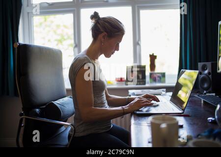 Frau, die von zu Hause aus mit einem Laptop im Heimbüro arbeitet Stockfoto