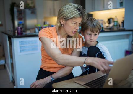 Mutter hilft Sohn mit Heimarbeit an Laptop Stockfoto