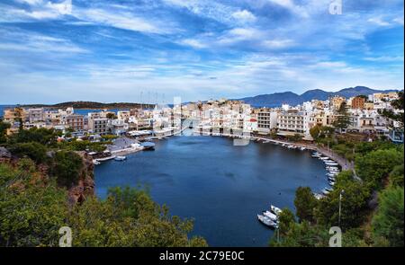 Farbenfrohe Sicht auf den Voulismeni See und Agios Nikolaos Stadt auf Kreta, Griechenland am Abend mit schönen Wolken am blauen Himmel. Stockfoto