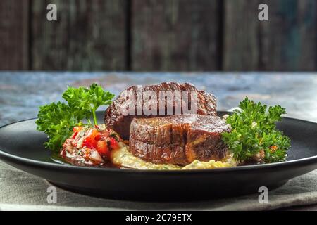 Rindermedaillons mit Tomatensalsa und Rahm Polenta Stockfoto