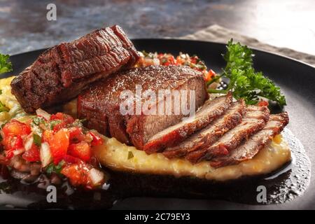 Rindermedaillons mit Tomatensalsa und Rahm Polenta Stockfoto