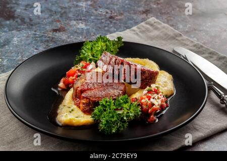 Rindermedaillons mit Tomatensalsa und Rahm Polenta Stockfoto