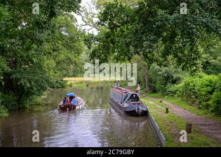 Ein schmales Boot und eine kleine Yacht auf dem Fluss Wey Navigation in der Nähe von Newark, Pyrford Surrey England Stockfoto