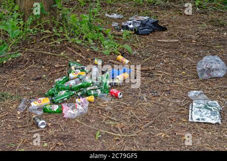 Leere Bierflaschen und gebrauchte Getränkedosen, die in einem ländlichen Ort entsorgt werden Stockfoto