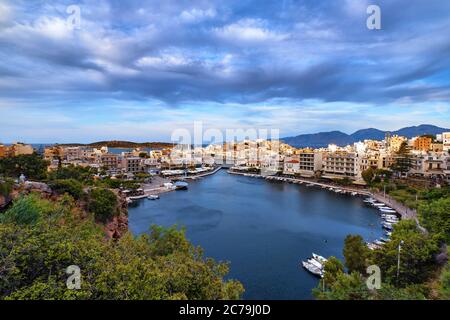 Farbenfrohe Sicht auf den Voulismeni See und Agios Nikolaos Stadt auf Kreta, Griechenland am Abend mit schönen Wolken am blauen Himmel. Stockfoto