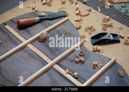 Geigenbaubank mit Werkzeug und Rückenteil einer akustischen Gitarre im Bau Stockfoto