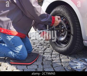 Mann, der das Rad auf dem Auto draußen mit dem Radschlüssel wechselt Stockfoto