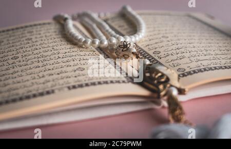 Heiliger Koran mit Rosenkranz Perlen mit rosa Hintergrund Stockfoto