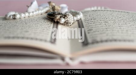 Heiliger Koran mit Rosenkranz Perlen mit rosa Hintergrund Stockfoto